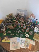 Overview photo showing entire collection of badger figurines, prints, mugs, and other related collectibles arranged on a table with green cloth.