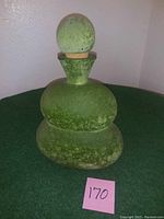 Front view of the large green glass decanter with stopper inserted, showing its shape and texture.