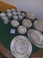 Full set of Mikasa Kabuki china including stacked plates, cups, and a covered sugar bowl on a green surface.