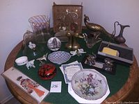 Overview of the entire lot showing various decorative items and collectibles arranged on a round table with green felt covering