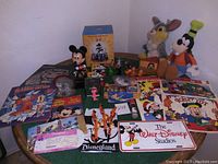 Photo of the full assortment of Disney items spread on a table, including plush toys, signs, brochures, figures, and novelty items.