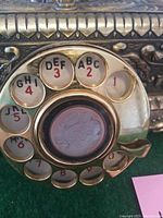 Close-up of rotary dial showing letters and numbers on metal dial plate with central decorative inlay