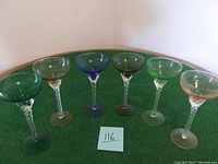 Front view of six colored vintage glassware stem glasses arranged side by side showing color variations.