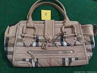 Full front view of the handbag showing handles, plaid pattern, zipper, lock and key attached.