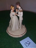 Full view of the Lenox porcelain figurine showing Cinderella and Prince Charming holding hands on the floral round base.