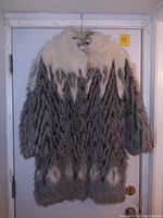 Front view of vintage fur coat with chevron pattern, showing white and gray fur and textured design.
