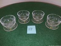 Four Waterford Crystal vintage cups with matching saucers arranged in a row on green felt.