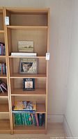 Full front view of the tall wood bookshelf showing six shelves and the items on some shelves, highlighting the condition and dimensions.