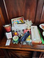 Overview of various candles and candle holders on wooden surface including tealight candles, glass holder, ceramic holder, and boxed taper candles.