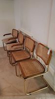 Four metal-framed cane chairs arranged in a row against a wall