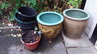 Front view of all four planters showing two large ceramic dragon patterned planters and two smaller plastic planters with soil residue.