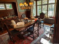 Wide view of dining room table showing six carved wood chairs with cushions