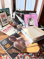 Assortment of over 20 vinyl LPs displayed on table, showing various artist sleeves