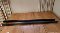 Two rolled-up Draper projector screens laid parallel on a wooden floor surface, showing full length of the screens.
