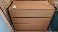 Front view of the light wood dresser showing the three drawers and flat fronts.