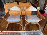 Front view of both chairs side by side showing scrolled arms and slatted X-frame bases