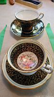 Two teacups and saucers on table, one with floral interior detailing