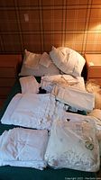 Vintage linens, cushions spread over bed including packaged linens