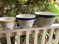 Front view of the set showing three different sized leaning mixing bowls with yellow, blue, and green rim colors
