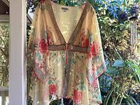 Coldwater Creek kimono blouse hanging on porch showing front with sleeves extended, floral print and tie front detail.