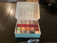 Box of 20 colorful, scented votive candles arranged in rows inside a mint-green box with open lid.