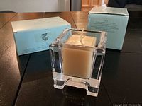 Votive candle holder with one candle inside and boxes in background