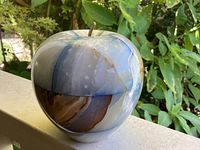 Close-up of the vintage onyx apple paperweight showing patchwork stone colors and metal stem.