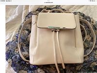 Front view of the beige WINK KANGAROO backpack showing flap and drawstring closure, gold-tone rectangular bar detail, and matching leather adjustable straps.