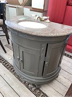 Photo showing curved wooden vanity with stone countertop, two front cabinet doors, and curved design details.