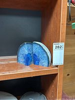 Pair of blue geode bookends on wooden shelf.