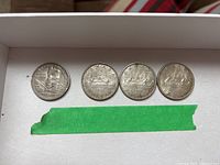 Four Canadian silver dollar coins displayed in a row, including one 1958 BC Centennial, one 1961, and two 1963 coins, all showing wear.