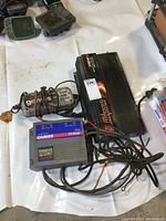 Photo displaying all three devices: NOCO Genius G7200 battery charger, Guest Charge Pro 15 Amp charger, and Motomaster 1750W inverter, all with attached wires and connectors.
