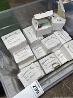 Plastic tote containing multiple Disney Christmas Magic boxed ornaments visible. Boxes labeled with character names and numbers.