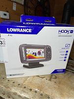 Box showing front side with image of the fish finder sonar device, branding Lowrance, model Hook 4x Bullet, with a 4-inch display and priced $150.
