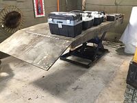 Overall view of lift with wood platform loaded with toolboxes