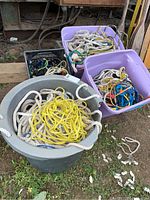 Four containers with various colors and thicknesses of marine rope, stacks of coiled ropes inside various bins and totes.