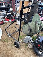 Full view of black tubular steel frame stand with front swivel caster wheels, rear fixed wheels, wooden block and motor clamp assembly.