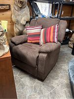 Front view of brown reclining chair with two striped throw pillows and visible armrests.