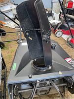 Front view of black snow discharge chute and auger intake area on the snow thrower.