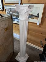 Full view of white plaster pillar plant stand showing fluted column and base