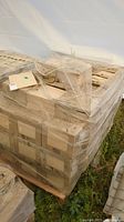 Pallet wrapped in plastic shrink wrap containing multiple cardboard boxes of tiles
