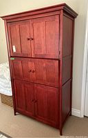 Front view of tall wood cabinet with three double-door sections, reddish-brown color, crown molding at top