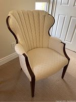 Front-left three-quarter view of wingback chair showing channel-tufted back and wooden arm frame