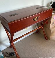 Angled front view of closed desk showing barley twist legs and brass hardware