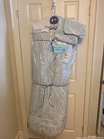 Comforter and pillow shams packaged together hanging on door