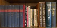 Shelf of books including Mark Twain collected works, classics, Greek mythology books, and novels.