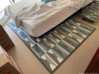 IKEA Vistrup rug under bed showing geometric pattern in blue, gray, white, and brown.