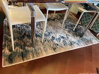 Full view of the Linart geometric motif rug under a glass table with white chairs to show design and scale.