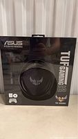 Front of the sealed retail packaging showing Asus TUF Gaming H5 headphones with logo and branding.