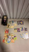 Top-down view of assorted loose Pokémon cards in piles along with three sealed Yu-Gi-Oh booster packs on table next to a box.